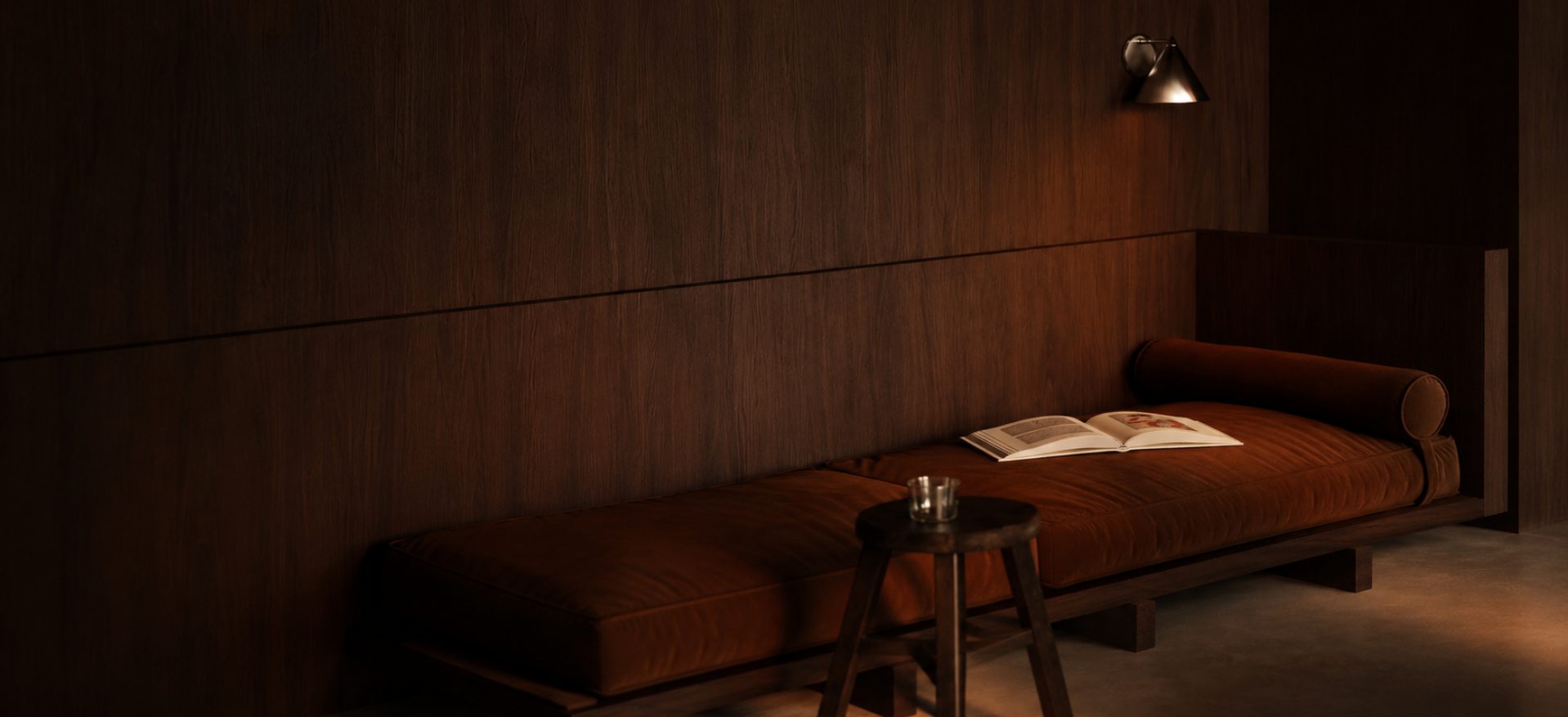 A walnut-panelled wall with a tan leather daybed set against it, lit by a single wall light.